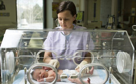 Bebé prematuro en incubadora con enfermera